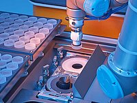 Robotic arm handling components on an automated tray system inside industrial machine