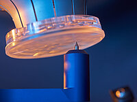 Glass lens in a machine above a fine probe or measuring tip during the manufacturing process