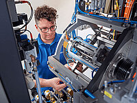 Technician servicing or repairing a complex industrial machine with visible cables and components