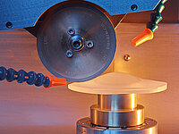 Laboratory cutting machine with a circular blade processing an irregularly shaped sample.