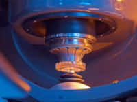 Close-up of a machine processing a glass lens with a rotating precision tool.