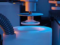 Close-up of a machine polishing or processing an optical lens.