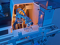 Automated industrial machine with side touchscreen monitor and open working area for precise manufacturing processes.