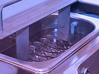 Semiconductor wafers submerged in a cleaning or chemical processing bath inside a stainless steel container.