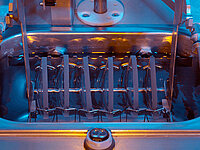 Close-up of semiconductor wafers aligned in a metal rack during chemical bath processing.