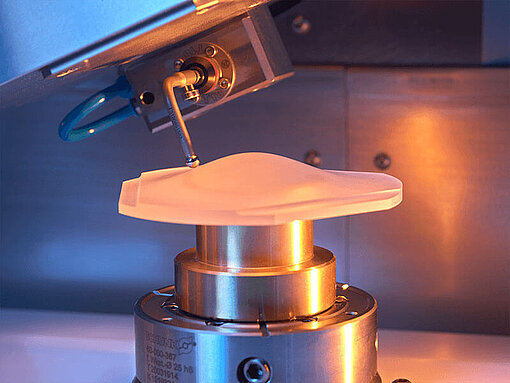 Laboratory machine with a probe analyzing an irregularly shaped sample on a metallic holder.