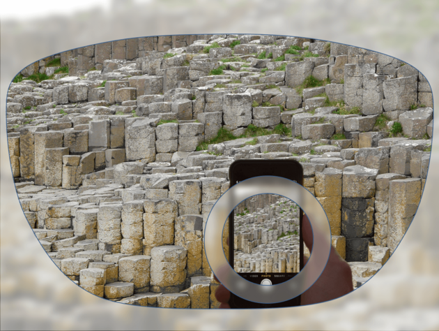 View through a pair of glasses showing stone formations, with a smartphone in the foreground capturing the same scene.