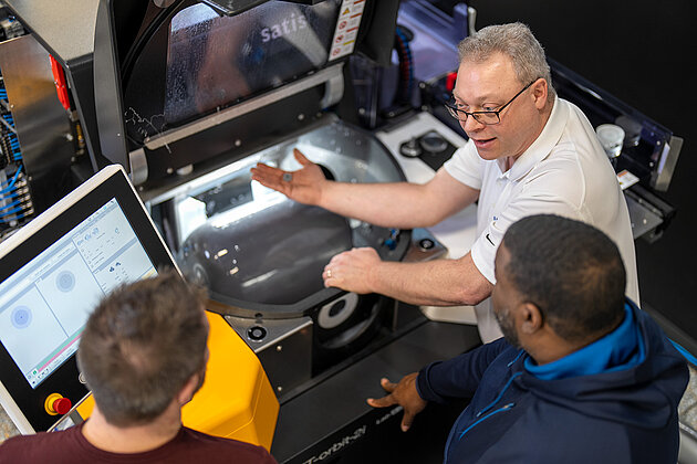 Instructor demonstrating industrial machine operation to two participants