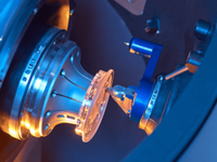 Close-up of a machine processing a glass lens between two precision tools