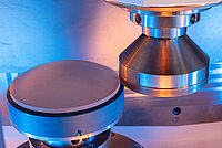 Laboratory equipment with a conical tool aligned above a cylindrical test sample