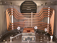 Interior of a vacuum coating machine showing copper coils and processing components.