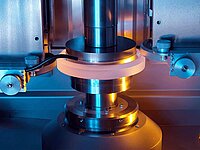 Close-up of an automated machine processing a circular ceramic or glass component