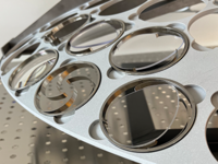 Close-up of semiconductor wafers placed in a circular metal holder with multiple slots.