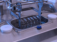 Semiconductor wafers held in a metal rack being processed inside a chemical bath container.