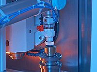 Close-up of robotic arm operating mechanical component inside industrial machine