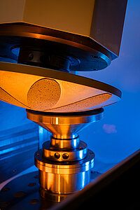 Close-up of laboratory equipment with a conical tool pressing onto a cylindrical sample during testing