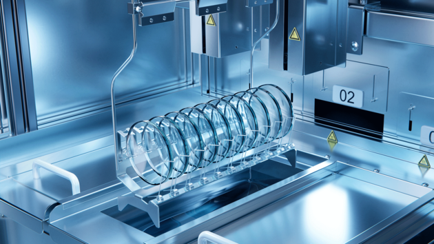Semiconductor wafers arranged in a holder inside an automated processing chamber with metallic surfaces.