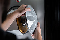 Person installing or adjusting a circular tool component on laboratory equipment