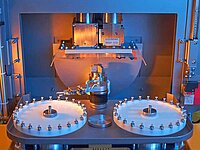 Industrial machine interior with two circular rotating components and precision tool arm