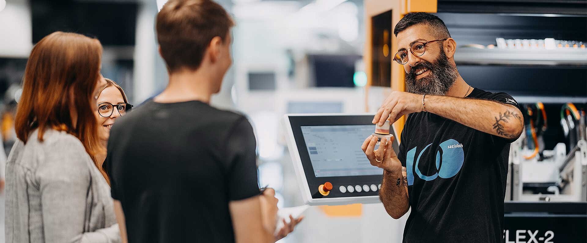 Instructor demonstrating industrial machine to two people in a training session