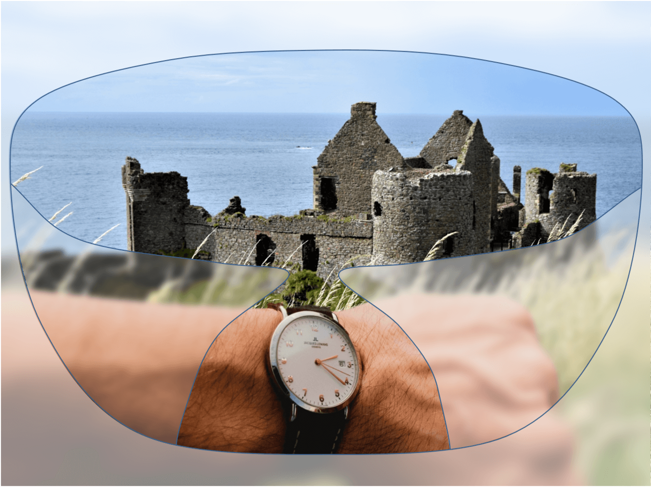 View through a pair of glasses showing ruins of a stone castle by the sea, with a wristwatch visible in the foreground.