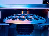 Industrial machine with circular metal component and multiple openings inside a chamber