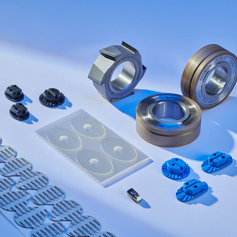 Collection of industrial components including bearings, inserts, and precision parts on a light surface