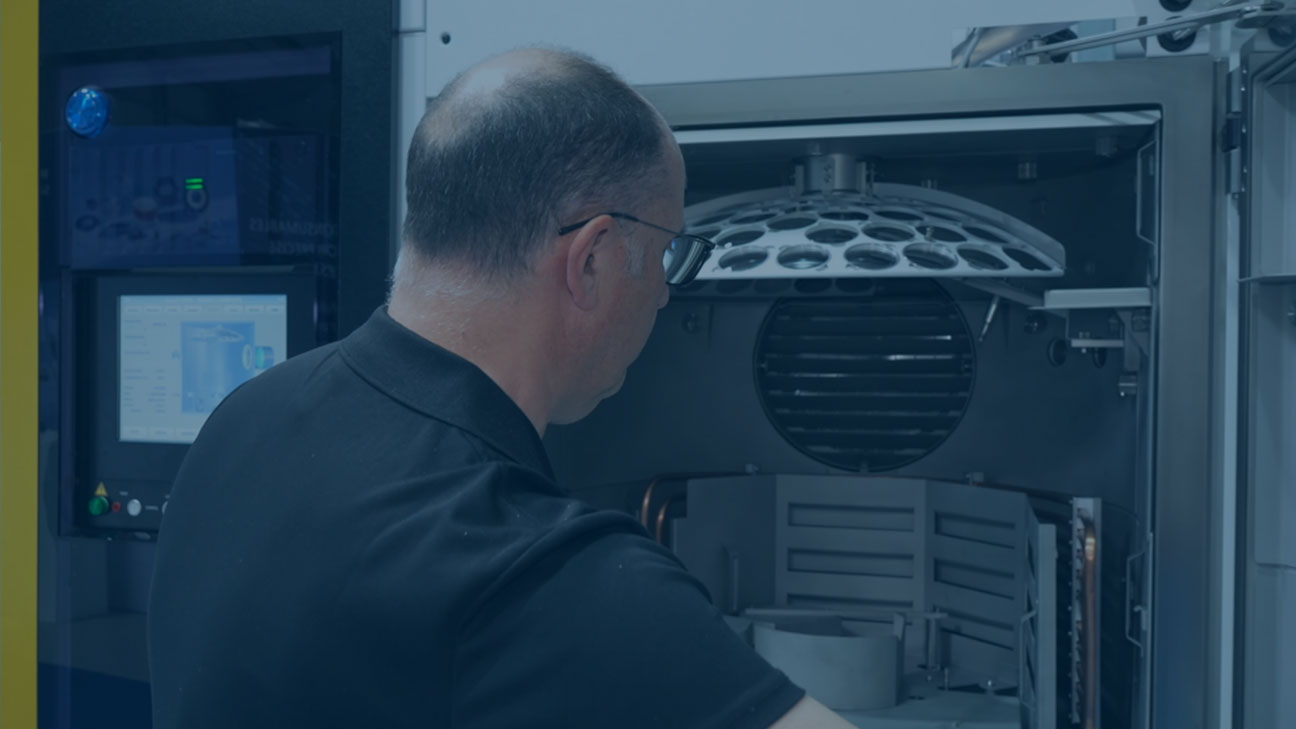 Technician operating a semiconductor processing machine while loading wafers into a circular holder.