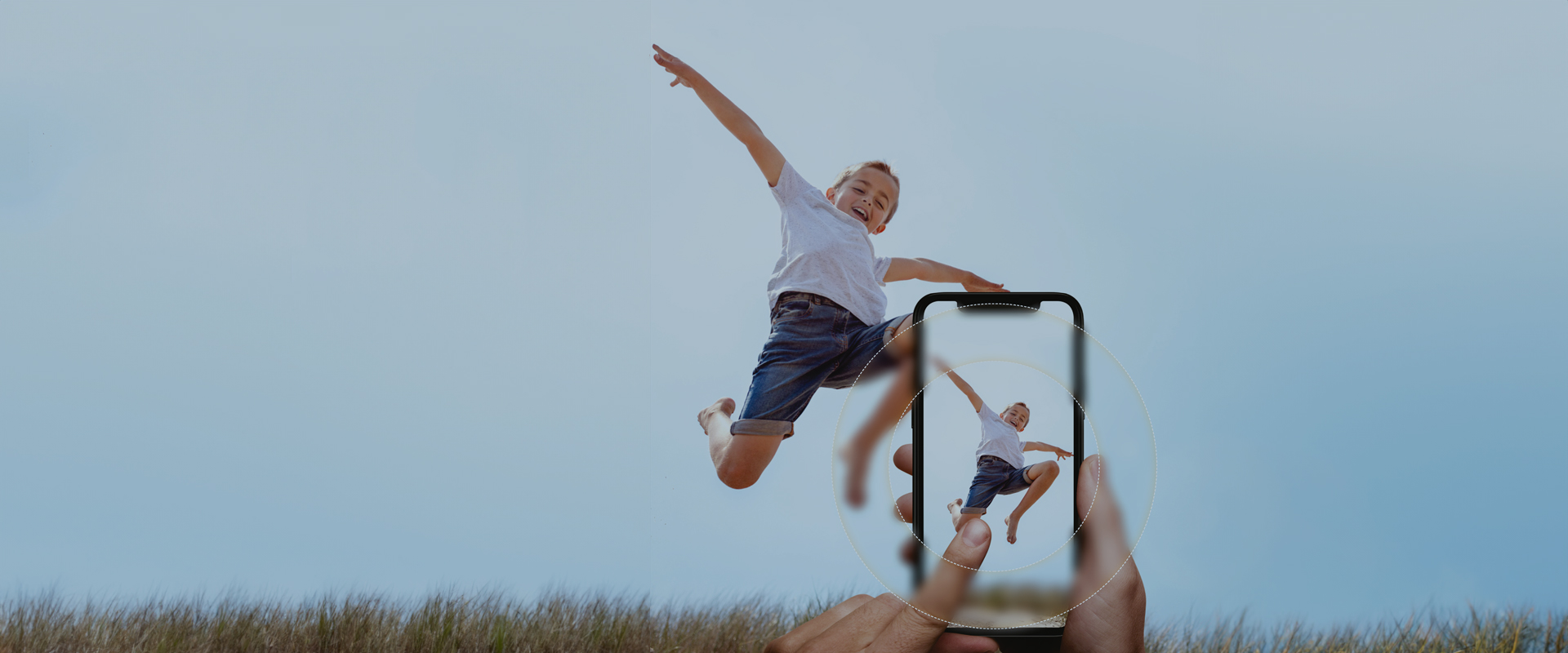 Experience seamless vision Person jumping joyfully in the air outdoors, while being photographed with a smartphone in the foreground.
