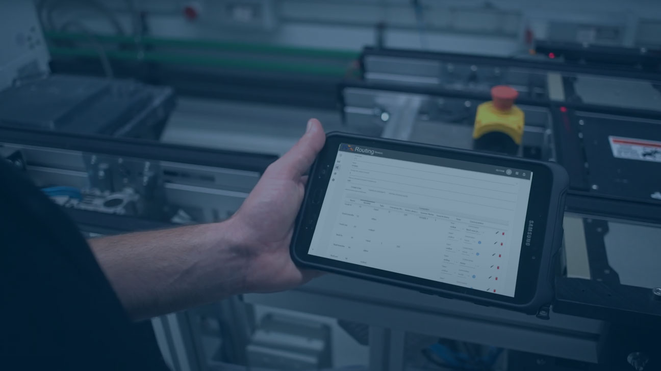 Person holding a tablet displaying data in front of automated laboratory equipment.