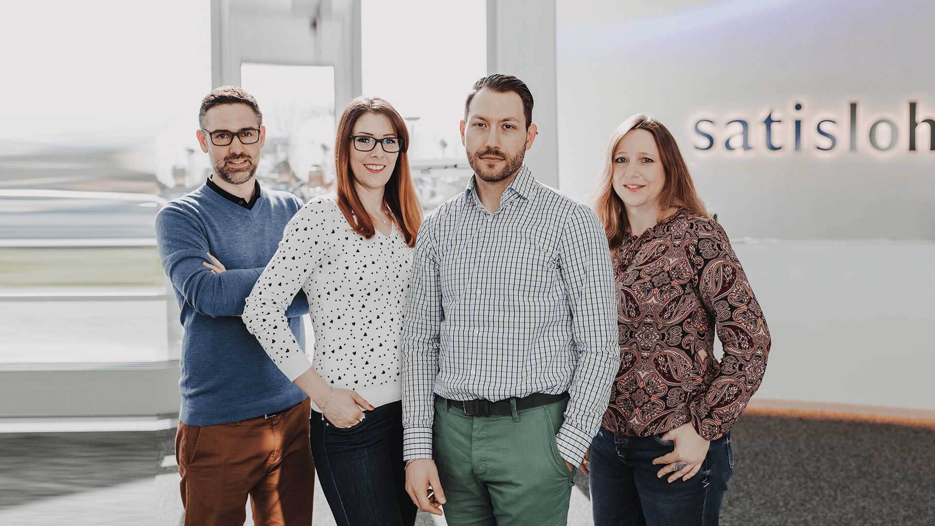 Group of Satisloh employees smiling into the camera.